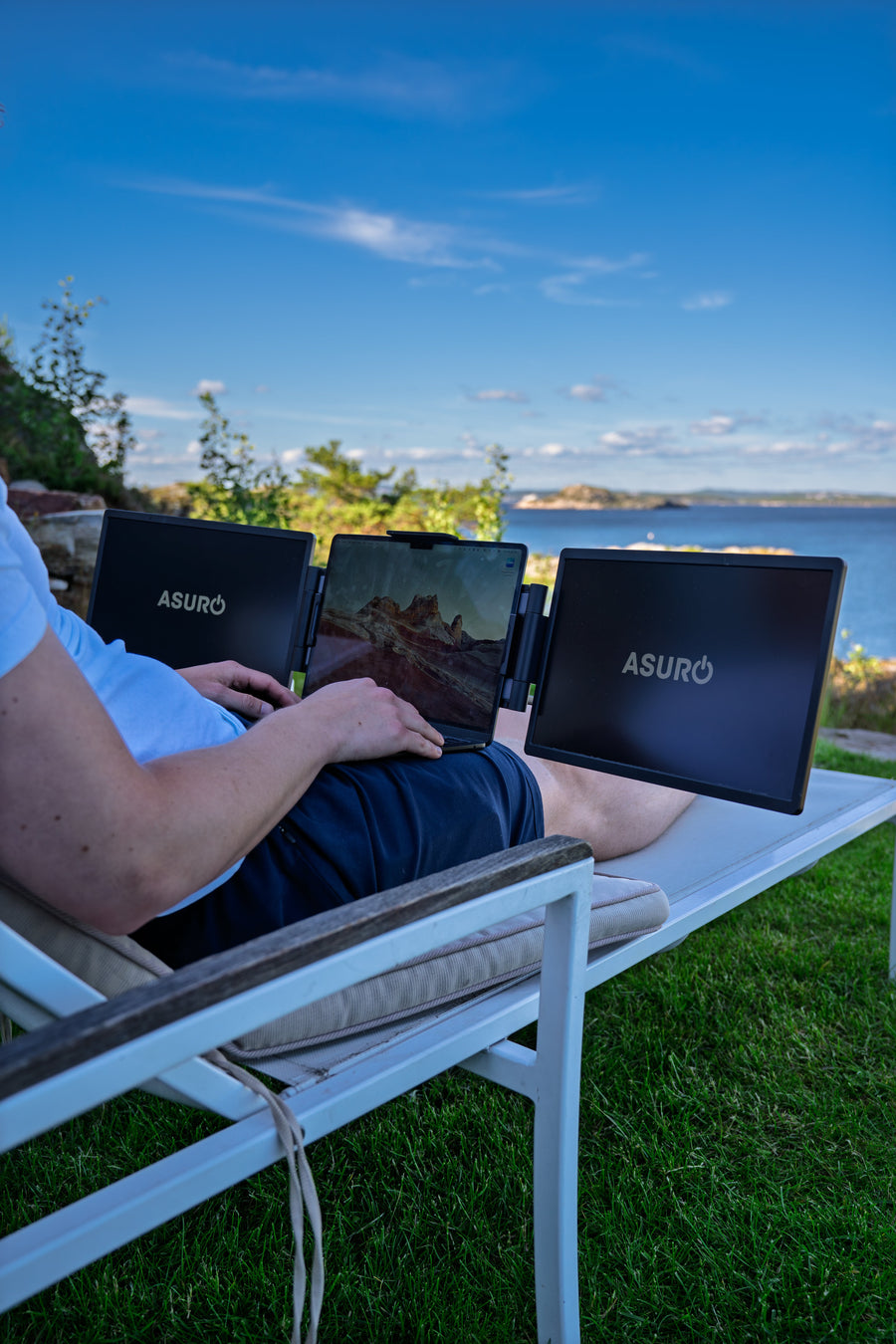 Person som jobber tilbakelent utendørs med laptop og to sideskjermer