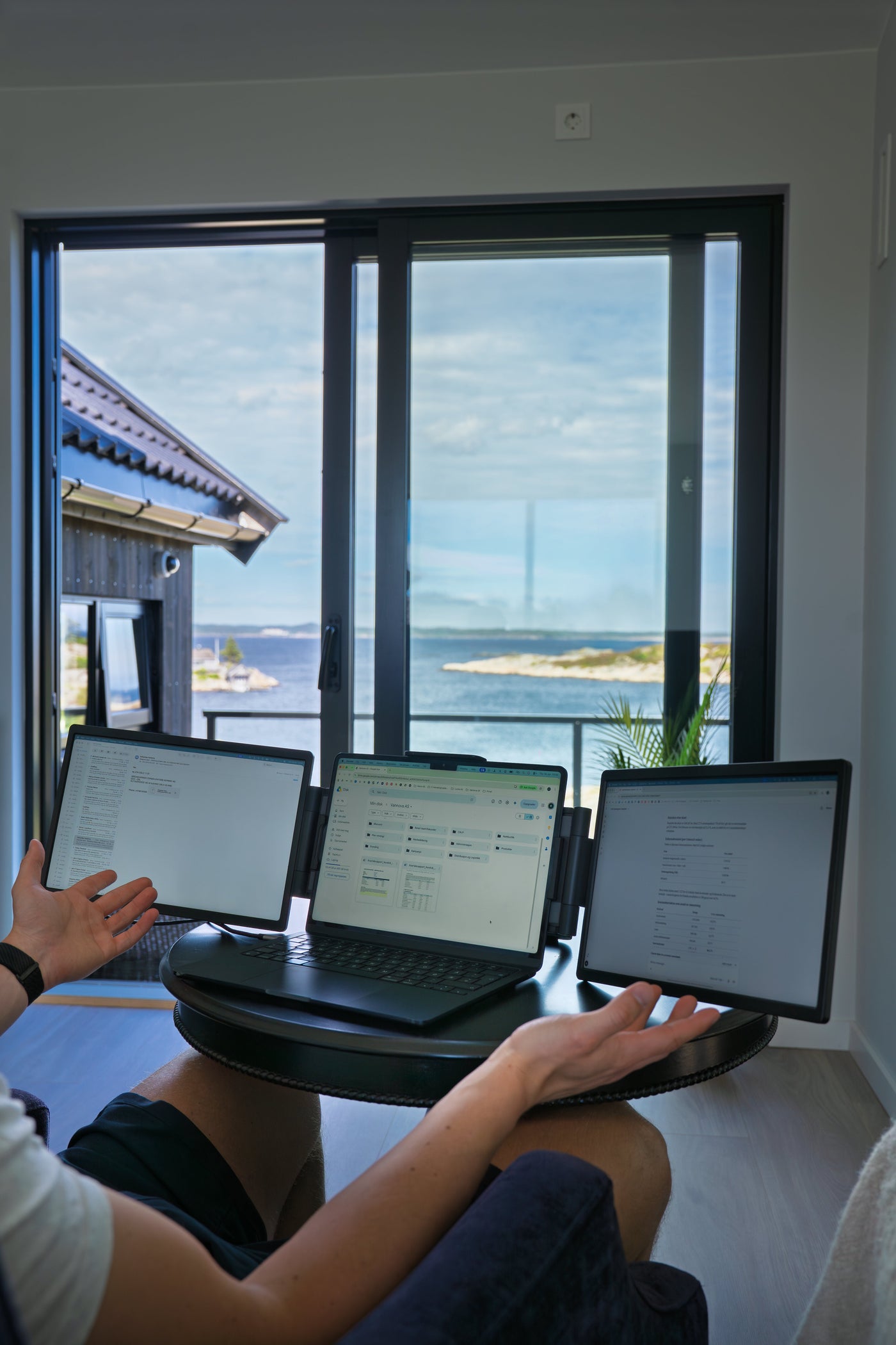 Nærbilde av arbeid på laptop med to ekstra skjermer