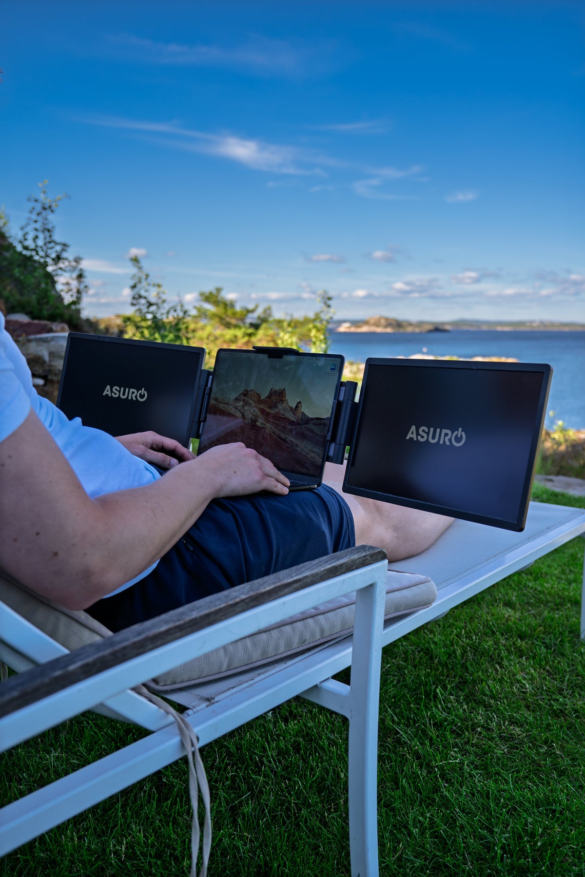 Person som jobber tilbakelent utendørs med laptop og to sideskjermer